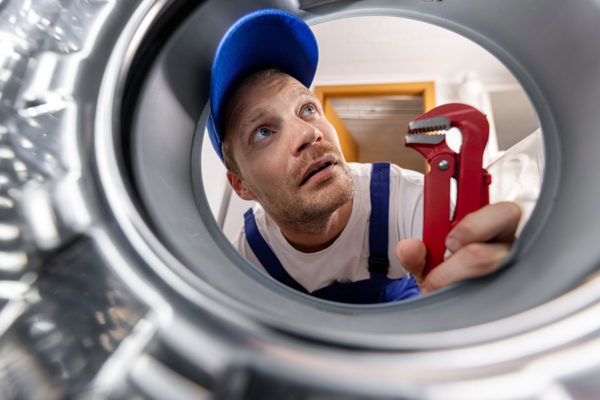 washing machine repair service. repairman looking inside drum